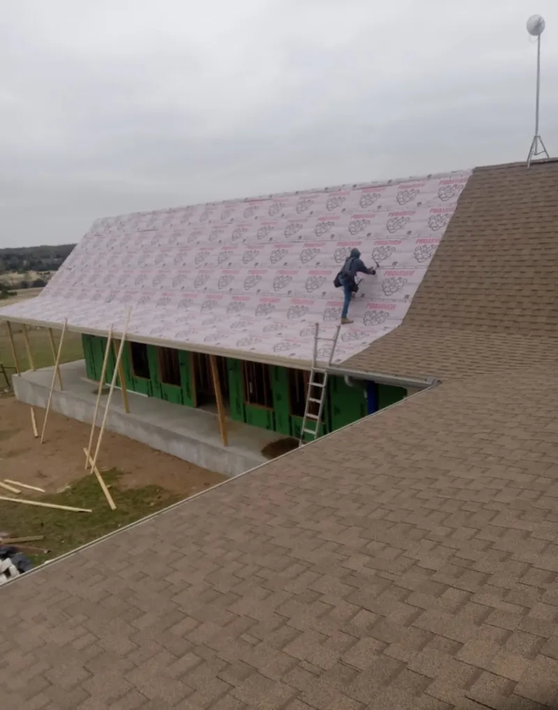 Worker preparing underlayment for a metal roof installation in Clarinda